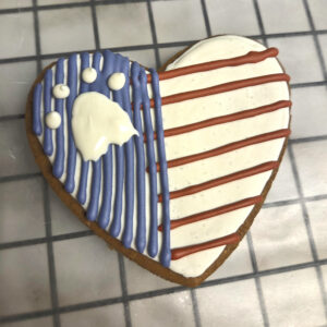 Heart shaped dog treat with dog friendly icing on it to make a flag and a dog foot print on it.